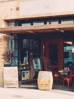 Cozy cafe entrance with wooden barrels and rustic decor, inviting street view.