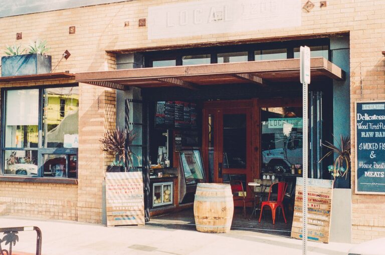 Cozy cafe entrance with wooden barrels and rustic decor, inviting street view.